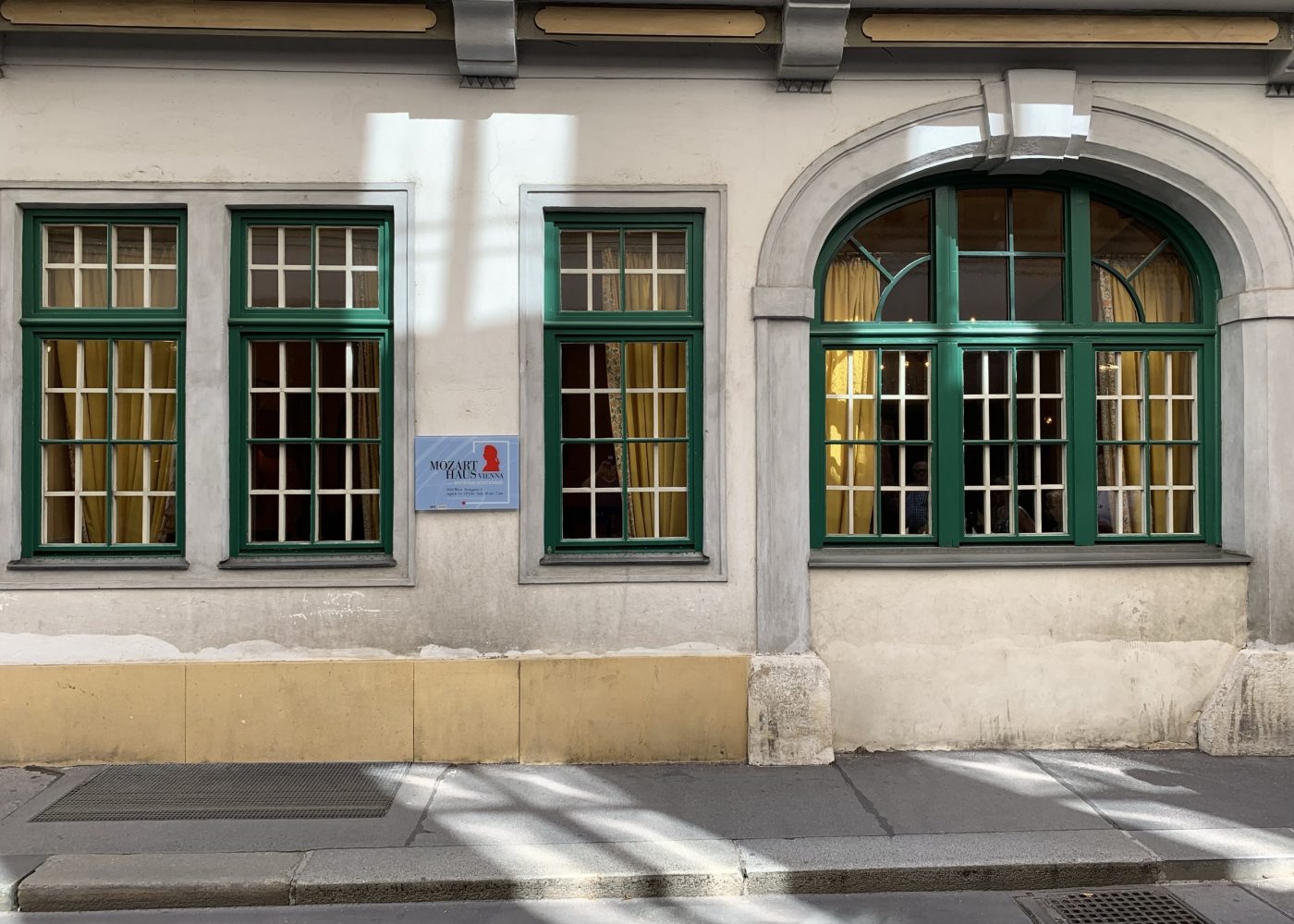 The facade of Mozarthaus Vienna on Domgasse, with its green window frames and the museum plaque