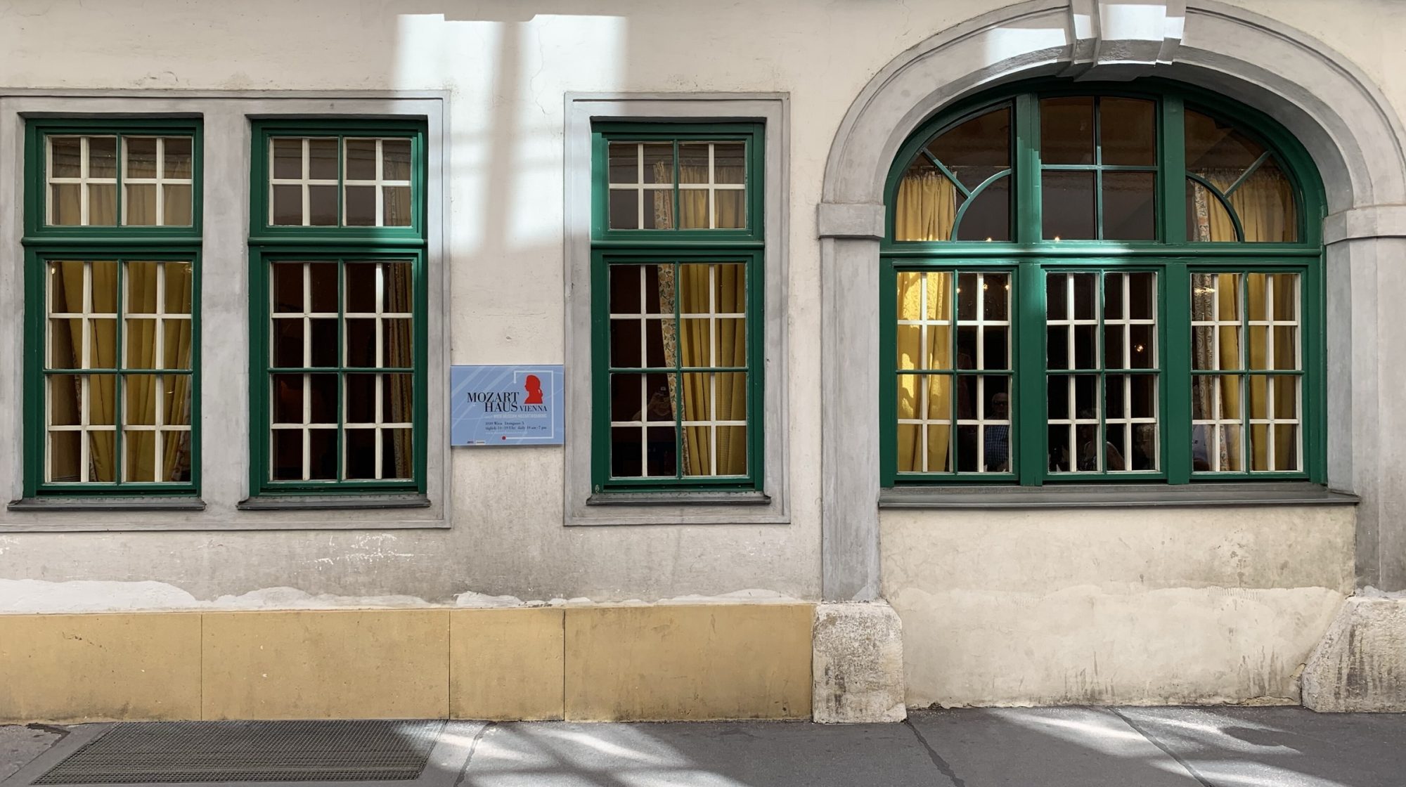 The facade of Mozarthaus Vienna on Domgasse, with its green window frames and the museum plaque