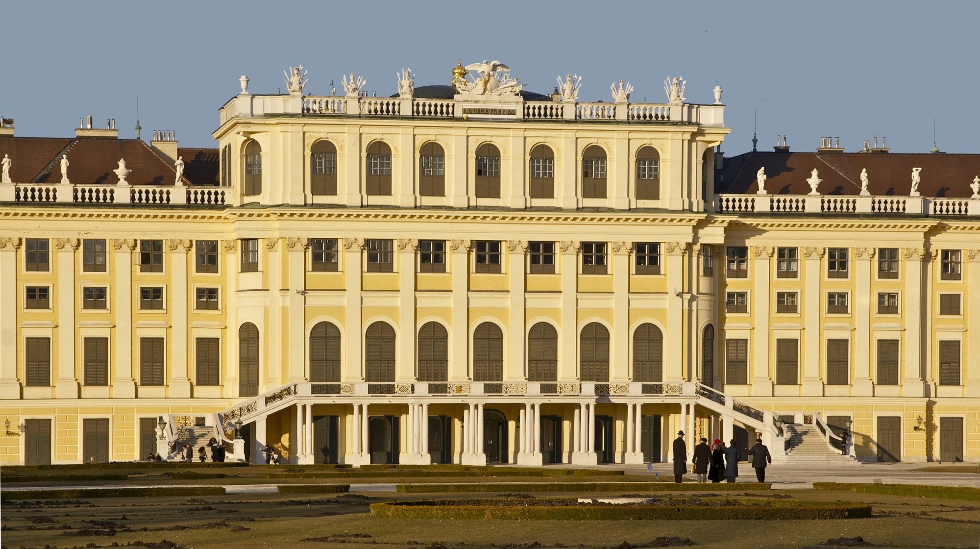 The yellow garden facade of Schönbrunn Palace in late afternoon light, seen across the parterre