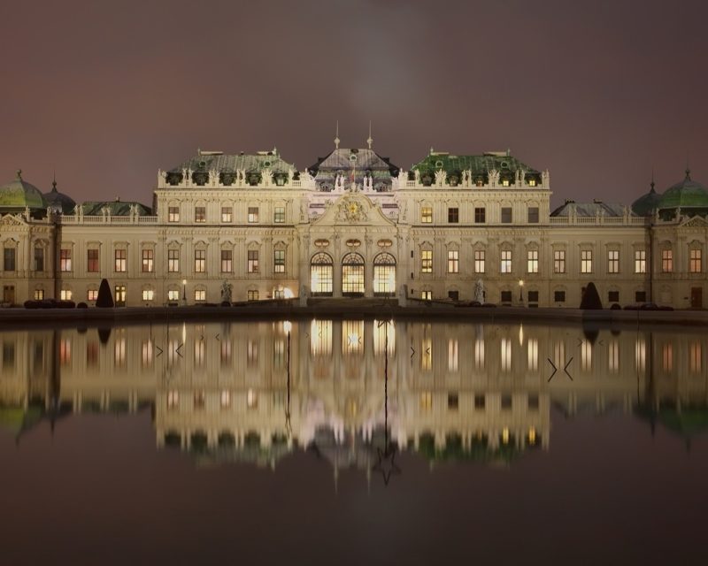 The Upper Belvedere lit at dusk and reflected in still water