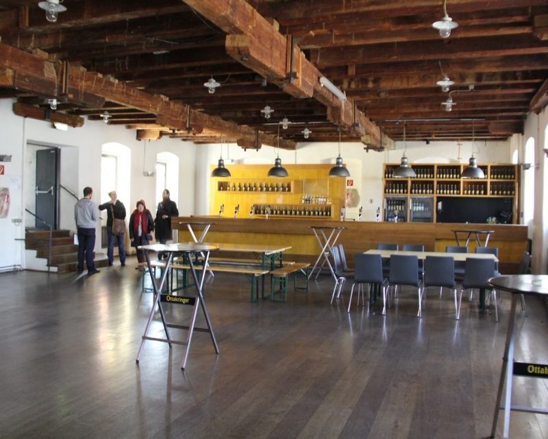 The Hoppenboden inside the brewery: a long bar and tables under old timber beams