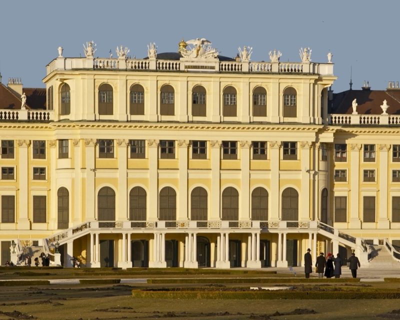 The golden garden facade of Schönbrunn Palace with visitors on the forecourt